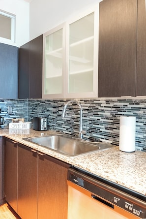 A modern kitchen with dark wood cabinets, a stainless steel sink, a coffee bar sign, and a dishwasher. - Charming 2-Bedroom apartment with AC In perfect Cincinnati (Cincinnati)