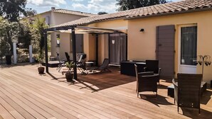 A wooden deck with outdoor furniture, including chairs and a table, and a covered area with a pergola. - Amazing home in Collias (Collias)