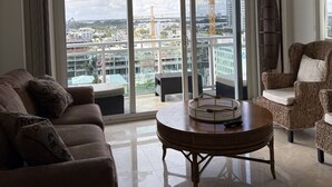 Ein geräumiges Wohnzimmer mit einem großen Schiebeglasfenster, das auf einen Balkon mit Blick auf die Stadt führt.