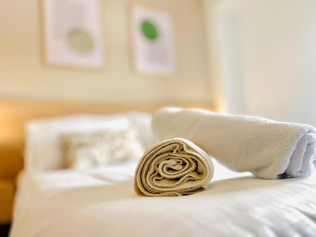 A neatly made bed with a rolled towel and a folded blanket in a hotel room.