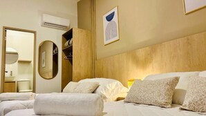 Ein Hotelzimmer mit zwei Betten, einem Holzkopfstück, einem Spiegel, einem Kleiderschrank und einem gerahmten Kunstwerk an der Wand.