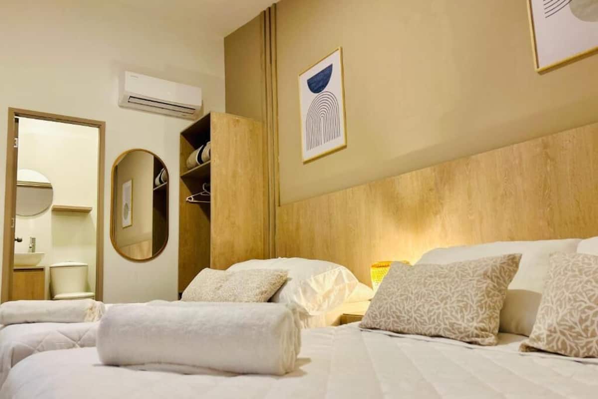 A hotel room with two beds, a wooden headboard, a mirror, a wardrobe, and a framed artwork on the wall.