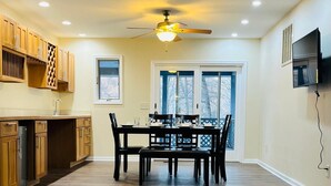 A spacious kitchen with wooden cabinets, a dining table set for four, and a ceiling fan. - Spacious Camelback Retreat w/ Fireplace (Henryville)