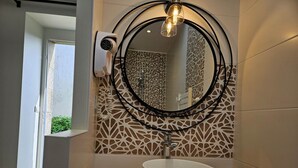 A bathroom with a round mirror, a white sink, and a decorative wall with geometric patterns. - Bed and Breakfast Île d'Hoëdic (BELZ)