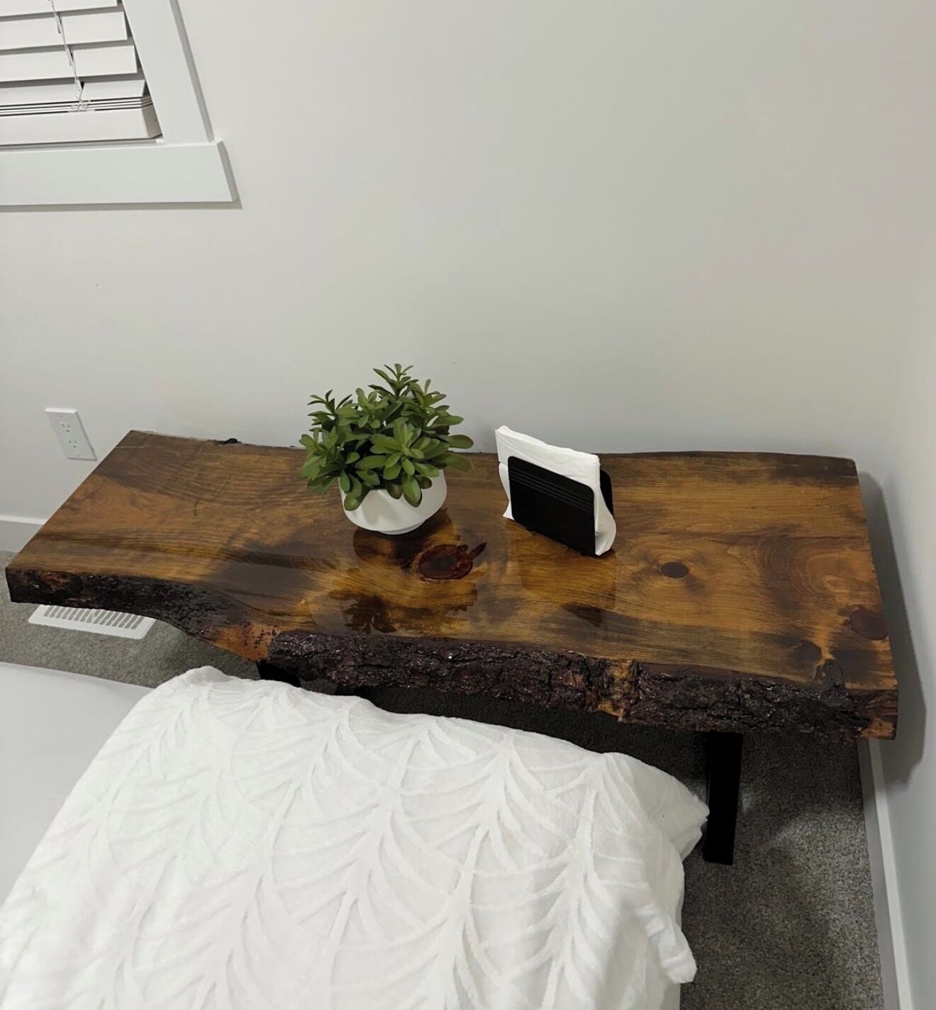A wooden table with a plant and a white object on it.