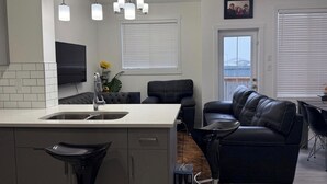 Una cocina moderna con una isla integrada, sofá de cuero negro y un comedor con mesa y sillas.
