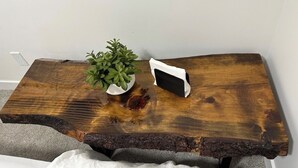 Una mesa de centro de madera con una planta y un objeto blanco encima.