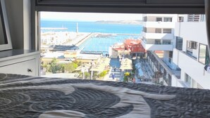 Une chambre d’hôtel avec vue sur une zone côtière, comprenant un port de plaisance et des bâtiments.