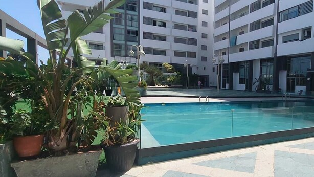 Un bâtiment moderne doté d’une piscine centrale, entouré de plantes en pot et dont le sol est recouvert de carreaux.