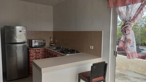 Une cuisine compacte équipée d’un réfrigérateur, d’un grille-pain, d’un évier et d’une cuisinière.