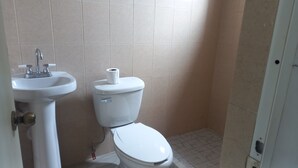 Une salle de bain avec un lavabo blanc, des toilettes et des murs carrelés.