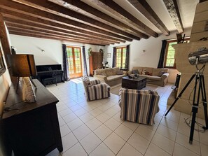 A spacious living room with a piano, sofas, a coffee table, and a tripod. - Le Tuquet de Saint Chamassy, private swimming pool (ST CHAMASSY)