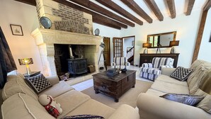 A cozy living room with a stone fireplace, wooden beams, a sofa set, and a coffee table. - Le Tuquet de Saint Chamassy, private swimming pool (ST CHAMASSY)
