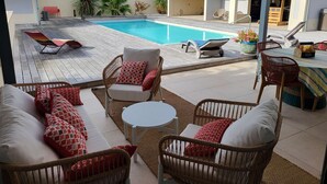 A covered outdoor area with a pool, wicker furniture, and a dining table. - Ref 038 - Exceptional villa with private pool and jacuzzi in the center of Soulac-sur-Mer (SOULAC SUR MER)