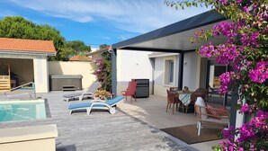 A poolside area with lounge chairs, a barbecue grill, and a covered seating area with a table and chairs. - Ref 038 - Exceptional villa with private pool and jacuzzi in the center of Soulac-sur-Mer (SOULAC SUR MER)