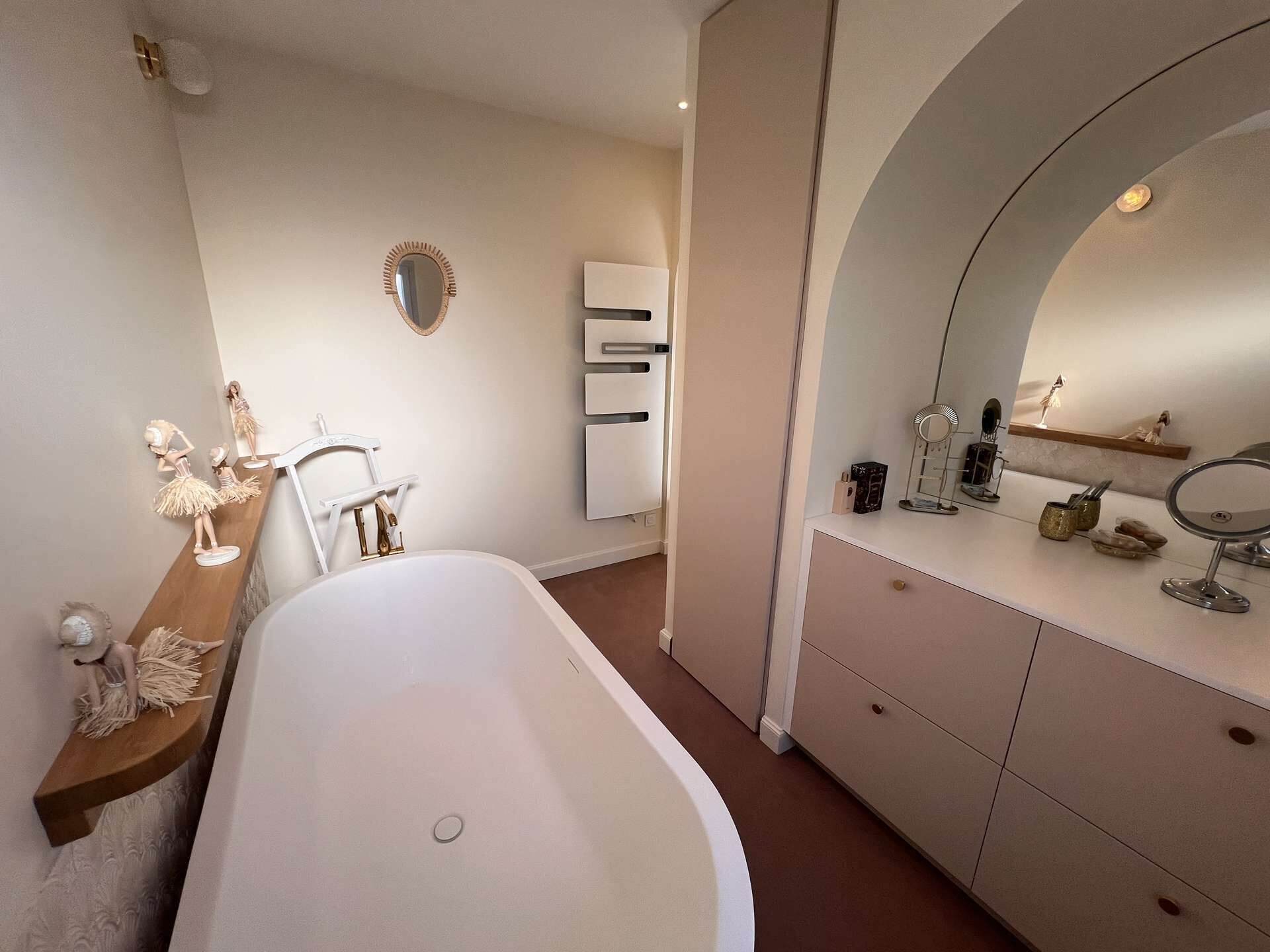 Een moderne badkamer met een vrijstaand bad, een wastafel met spiegel en een plank met toiletartikelen.