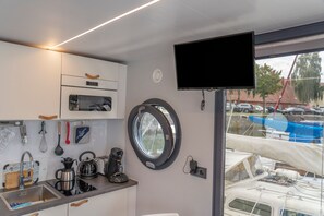 Eine Küche mit Fenster, einem Flachbildfernseher und verschiedenen Küchengeräten.