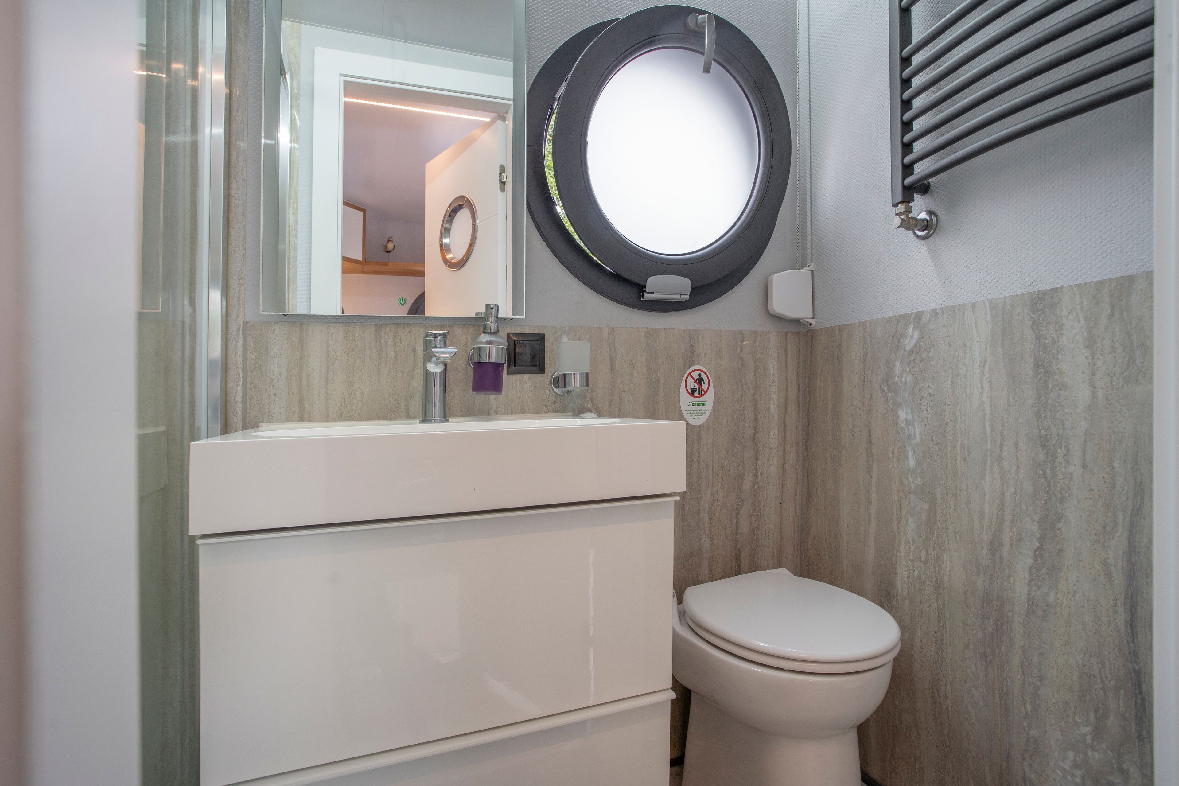 Ein modernes Badezimmer mit Toilette, Waschbecken und Spiegel.