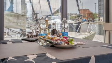 Een tafel met een welkomstbord, flessen en eten.