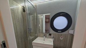 A bathroom with a glass-enclosed shower, a sink with a mirror above it, and a toilet.