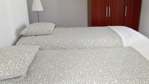 A bed with patterned bedding, a bedside lamp, and a wooden wardrobe. - Refuge - "Vivenda Chã" (Ribeira Funda)