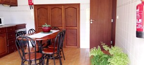 A dining area with a wooden table, chairs, a red decorative item, and a fire extinguisher mounted on the wall.