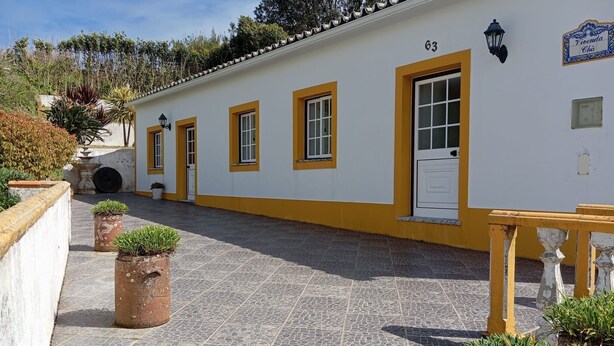 A building with numbered doors, a tiled courtyard, and potted plants. - Refuge - "Vivenda Chã" (Ribeira Funda)
