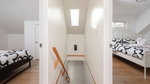 Ein Schlafzimmer mit Etagenbett, kleinem Fenster und einer Tür zu einem anderen Raum.