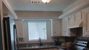 A kitchen with light wood cabinets, a black refrigerator, a sink, and a stove. - 3-bedroom house in peaceful Magnolia with cool AC on 7.5 acres. (Magnolia)