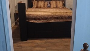 A bedroom with a wooden bed frame, a dark headboard, and a patterned bedspread. - 3-bedroom house in peaceful Magnolia with cool AC on 7.5 acres. (Magnolia)