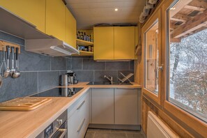 Een moderne keuken met houten kastjes, een roestvrijstalen spoelbak en een raam met uitzicht op een besneeerd landschap.
