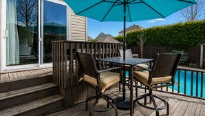 Une terrasse avec une table et des chaises, une piscine et une clôture en bois.