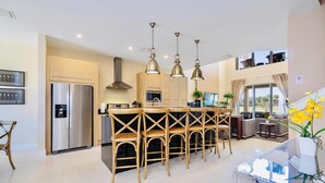 A modern kitchen with a central island, stainless steel appliances, and pendant lighting. - Beautiful Magic Village Townhome Minutes from Disney (Kissimmee)