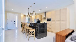A modern kitchen with a central island, bar stools, and pendant lighting. - Beautiful Magic Village Townhome Minutes from Disney (Kissimmee)