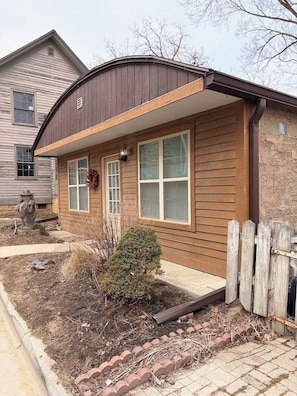 A residential house with a brown exterior, a front porch, and a small garden area.