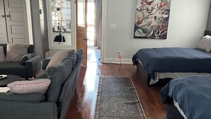 En moderne stue med en grå sofa, en blå sofa, et stort tæppe og et billede på væggen.