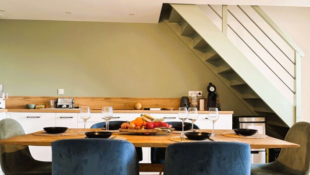 Una cocina moderna con encimera de madera, una mesa de comedor con cuatro sillas y una escalera.