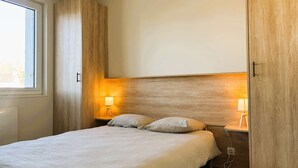 Un dormitorio con una cama, dos lámparas de noche, un ventanal y paredes de madera.