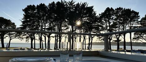 Een tafel voor twee met uitzicht op zee en bomen.