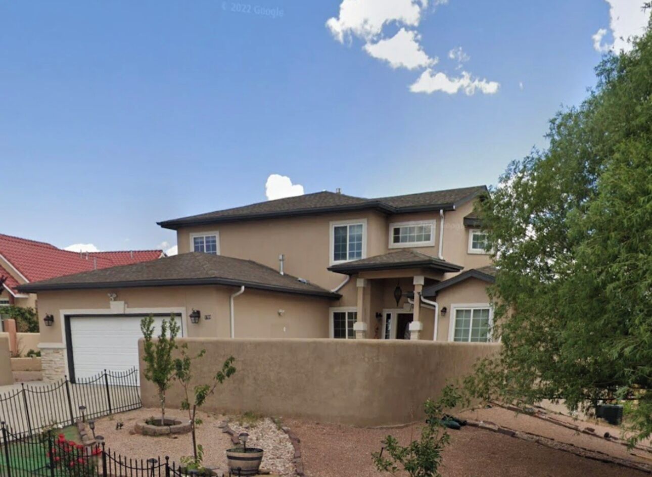 A two-story house with a garage, a covered porch, and a landscaped front yard.