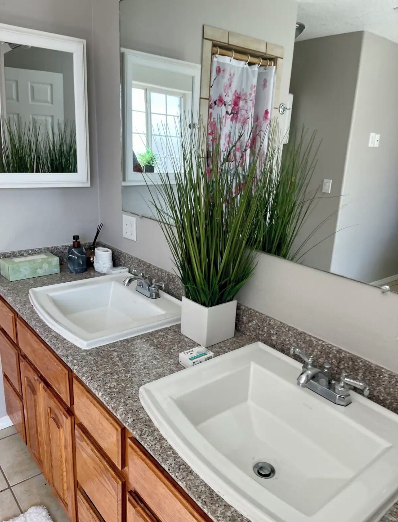 A bathroom with two white sinks, a mirror, and a shower curtain with a floral pattern.
