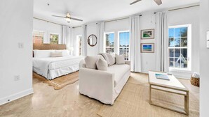 Una habitación amplia con cama, sofá, mesa de centro y ventilador de techo.