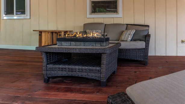 A wicker outdoor seating area with a fire feature, wooden flooring, and a view of the outdoors. - The Rose House: Spacious Retreat w/ Fire Pit Deck/ near expo & Airport/Sleeps 8 (Central Point)