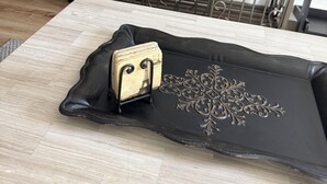 Ein Zimmer mit einem an der Wand befestigten Fernseher, einem schwarzen Metallgitter und einem Tisch mit einer dekorativen Tablett.