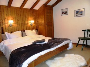 Ein Schlafzimmer mit Holzwänden, einem Bett, zwei Wandlampen und einem Sessel.