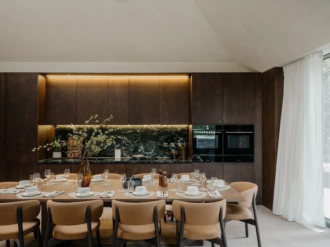 A modern dining area with a long table set for six, surrounded by chairs.