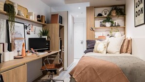 A compact bedroom with a bed, a desk, and shelving. - Canvas Wembley Arthur House (Wembley)
