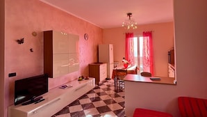 A living room with a checkered floor, a TV, a red sofa, and a chandelier. - Casa Dunà - Mareri apartments (Costarainera)