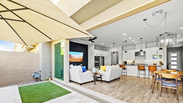 A modern kitchen with white cabinets, a central island, and a dining area with a wooden table and chairs. - Luna Luxe Rooftop Retreat | 3BR • 2.5BA • Pool (Scottsdale)