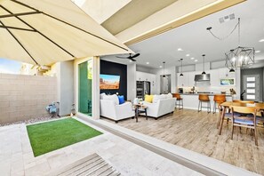 A modern kitchen with white cabinets, a central island, and a dining area with a wooden table and chairs. - Luna Luxe Rooftop Retreat | 3BR • 2.5BA • Pool (Scottsdale)